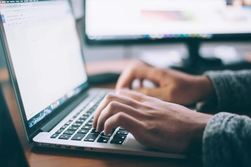 A person's hands typing on a laptop keyboard
